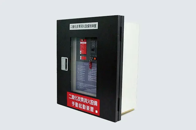 操作箱と一体化した二酸化炭素消火設備用制御盤（TC110-GS,GM型）の写真。黒い筐体の前面上部に「二酸化炭素消火設備制御盤」、下部に「手動起動装置」の赤い文字ラベルが見える。